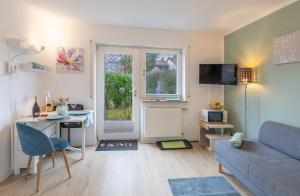 a living room with a couch and a table and a desk at Sonnige, ruhige Gartenwohnung mit Terrasse u. Garten in Oberhaching