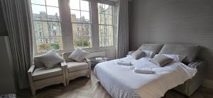 a bedroom with a bed and a chair and windows at 2 Bedroom Sofa bed in livingroom Castle View 1st floor sleeps 6 in Edinburgh