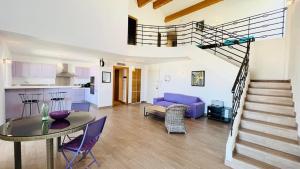 a living room with a table and a spiral staircase at Appartement Le Clos L'ILE ROUSSE in LʼÎle-Rousse