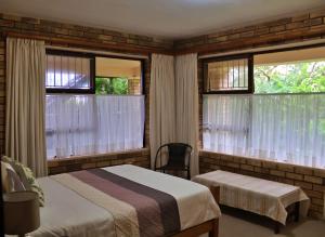 a bedroom with a bed and two windows at Remini in Jeffreys Bay
