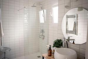 a white tiled bathroom with a sink and a mirror at Casa Bekkevé - Califa Casas in Vejer de la Frontera