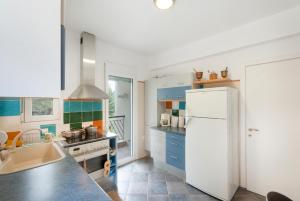 una cucina con armadi blu e frigorifero bianco di Vetas Vintage Villas - by RentalsPro Akti Elia Halkidiki a Elia Altre 10 foto