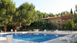 a swimming pool with white chairs and a building at Hostal Braseria Missamaroi in Tivissa