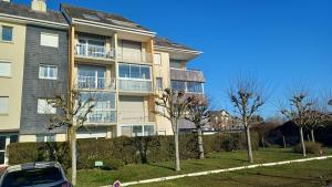 a large apartment building with trees in front of it at Cosy app near sea in Cabourg