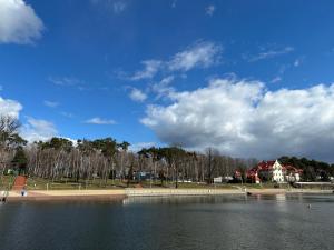 a view of a lake with a house in the background at Apartament Pod Żaglami 1 in Sława +11 photos