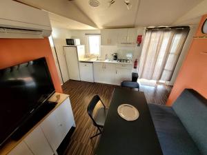 卡布勒通Mobil home Capbreton的小厨房和带黑桌的客厅