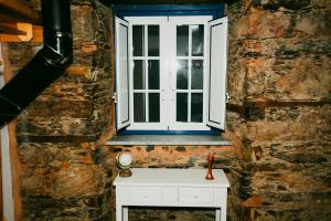 a window on a brick wall with a white table at Casa da Mata de Fajão in Pampilhosa da Serra +51 photos