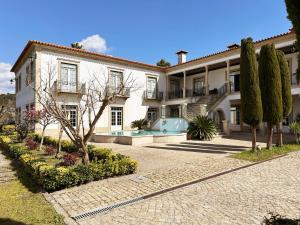 a large white house with a courtyard and trees at Casa do Fontão in Amarante