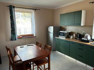 a kitchen with green cabinets and a table and a refrigerator at Noclegi nad Parsętą in Białogard