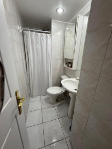 a white bathroom with a toilet and a sink at Depto Estudio 2 personas Las Condes in Santiago +12 photos