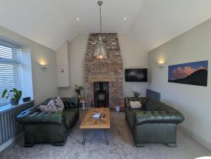 un salon avec deux canapés et une cheminée dans l'établissement Bandroom Cottage, à Kirkby Stephen