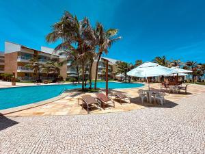 ein Pool mit Stühlen und Sonnenschirmen neben einem Gebäude in der Unterkunft Porto das Dunas Apê na Areia com Banheira Relaxante e acesso direto para a praia! Ideal para Famílias, Lazer e Conforto in Aquiraz + 29 Fotos