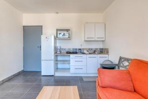 cocina con nevera blanca y sofá naranja en Appartement 4 personnes, en Balaruc-le-Vieux 19 fotos más