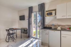 una cucina con mobili bianchi, un tavolo e una finestra di Studio Poussan a Poussan