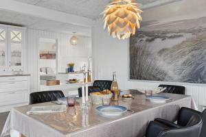a dining room with a table with chairs and a chandelier at Feriehus 1103 in Ringkøbing