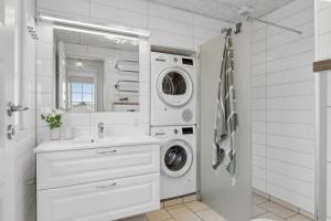 a white bathroom with a washing machine and a sink at Feriehus 1103 in Ringkøbing