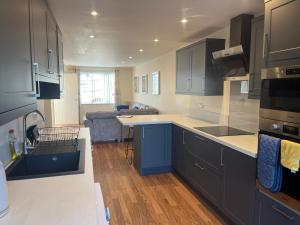 a kitchen with blue cabinets and a living room at Crombie House in Lincoln