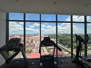 a gym with three cardio machines in front of a window at Cozy Stays Studio C - Kozi Square Kuching in Kuching