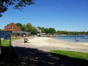 a sandy beach next to a lake with a building at Ferienhaus Seesternchen Aurich-Tannenhausen in Aurich