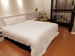 a large white bed in a room with a chair at 薇風情汽車旅館 - 湖內館 in Hu-nei