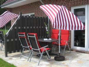 Una mesa y sillas con una sombrilla en un patio. en Sandperle, Ferienhaus, en Aurich