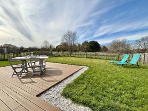 a patio with a table and two blue chairs at Maison neuve 3 pièces calme sur Oléron proche plage et commerces - FR-1-246A-298 in Dolus d'Oléron