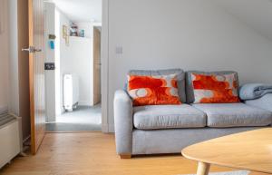 a living room with a gray couch with orange pillows at The Old Post Office in Saasaig