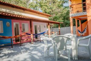 a patio with white chairs and a house at Suítes Serra do Cipó 2 in Santana do Riacho