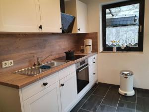 a kitchen with white cabinets and a sink and a window at Ferienwohnung Tigges in Müschede