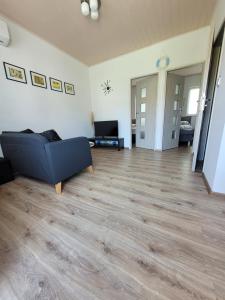 a living room with a blue couch and wooden floors at Domki Eridan, nad morzem in Wisełka