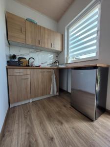 a kitchen with wooden cabinets and a stainless steel refrigerator at Domki Eridan, nad morzem in Wisełka