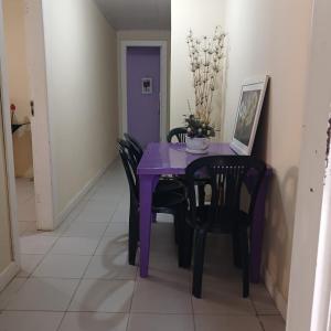 einen lila Tisch und Stühle in einem Zimmer in der Unterkunft Casa com 2 quartos e 2 banheiros na Lagoa do Centro in São Pedro da Aldeia