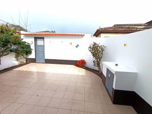 a white wall with a courtyard with a door at Casa do Bairro - O seu refúgio in Ponta Delgada