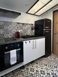 a kitchen with black and white tiles on the wall at La Cabane in Quiberville
