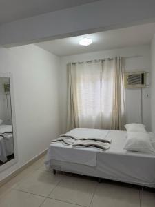 a white bedroom with a bed with a window at Itapuã - 4 Minutos da Praia - Quarto com Suíte in Vila Velha