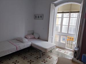 two beds in a room with a window at Old Merchant's Home in Cádiz