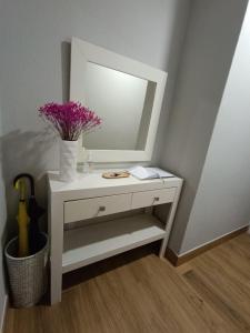 una mesa blanca con espejo y un jarrón con flores en Casa Filo, en Redondela