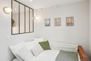 ein weißes Schlafzimmer mit einem weißen Bett und grünen Kissen in der Unterkunft Lavie Maison Central & Hot Tub in Bordeaux