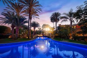 a swimming pool with palm trees and a sunset at R2 Rio Calma in Costa Calma