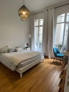 a white bedroom with a bed and a blue chair at Cosy and Modern near Champs-Élysées - Arc de Triomphe in Paris