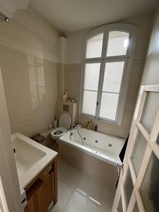 a bathroom with a tub and a toilet and a window at Cosy and Modern near Champs-Élysées - Arc de Triomphe in Paris