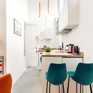 a kitchen with white cabinets and blue chairs at Cosy and Modern near Champs-Élysées - Arc de Triomphe in Paris