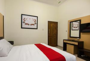 a bedroom with a bed with a red and white blanket at Esther Hotel in Silangit International Airport