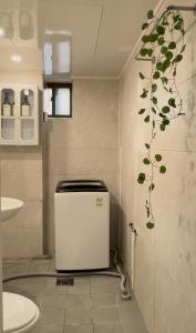 ein Badezimmer mit einem kleinen Kühlschrank und einer Pflanze an der Wand in der Unterkunft Sky Haenggung in Suwon