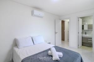 a white bedroom with a bed with two towels on it at Apto com vista incrível a 230m do Mar - MRE1101 in Perequê