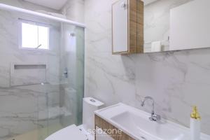 a white bathroom with a sink and a shower at Apto com vista incrível a 230m do Mar - MRE1101 in Perequê +16 photos
