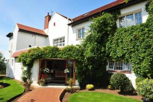 a white house with an ivy covered building at Highgrove House Hotel in Loans