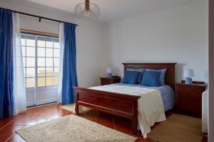 Un dormitorio con una cama con almohadas azules y una ventana. en Chalé da Malvarosa, en Atouguia da Baleia 5 fotos más