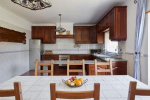 Una cocina con una mesa con un bol de fruta encima. en Chalé da Malvarosa, en Atouguia da Baleia
