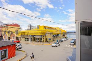 a yellow building with cars parked in a street at Gray Fox Apartments - Tower in Ushuaia